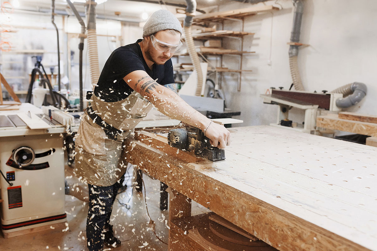 man in workshop using electric planer 